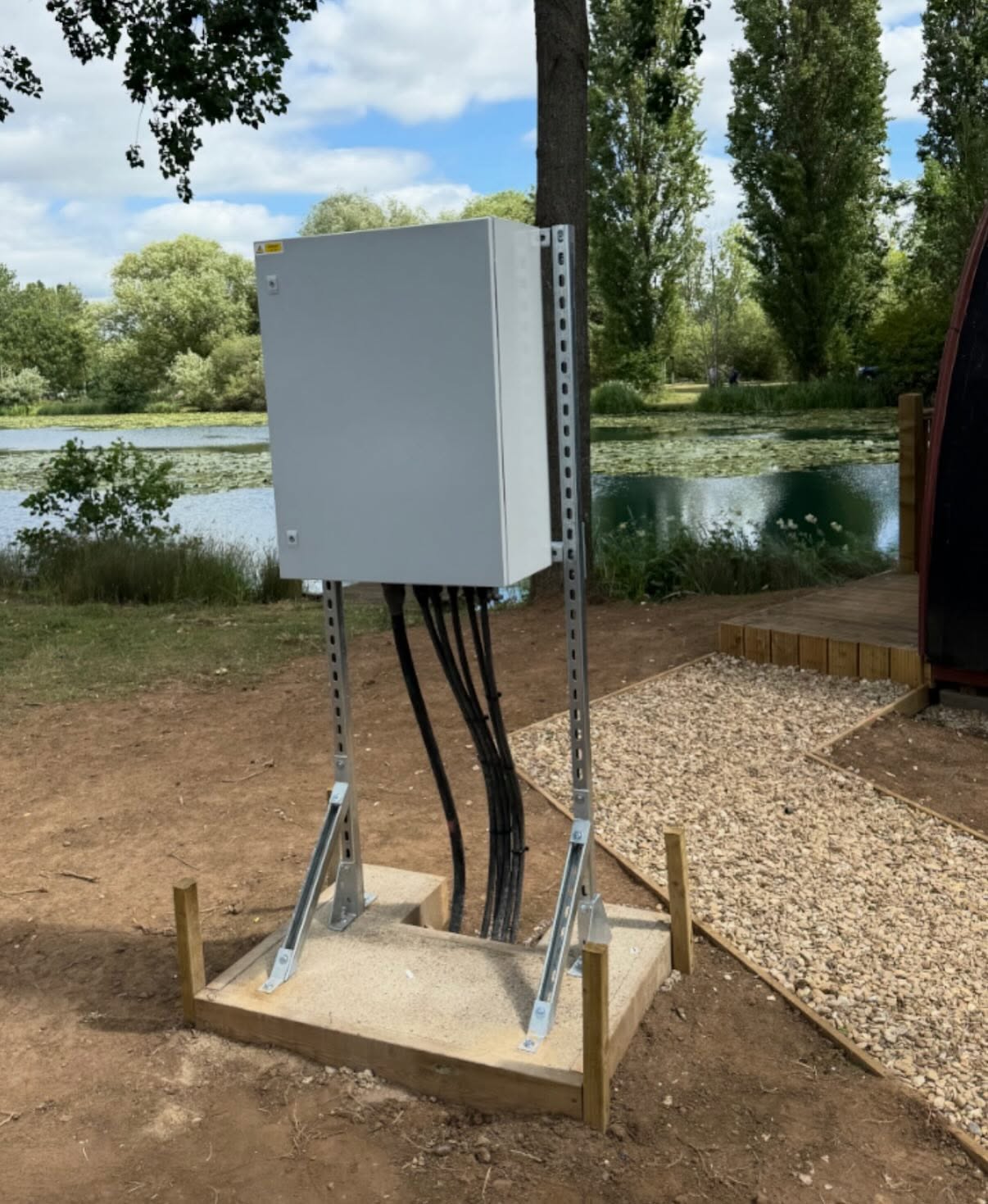 Outdoor distribution enclosure on unistrut beside a lakeside fishing pod in Northamptonshire