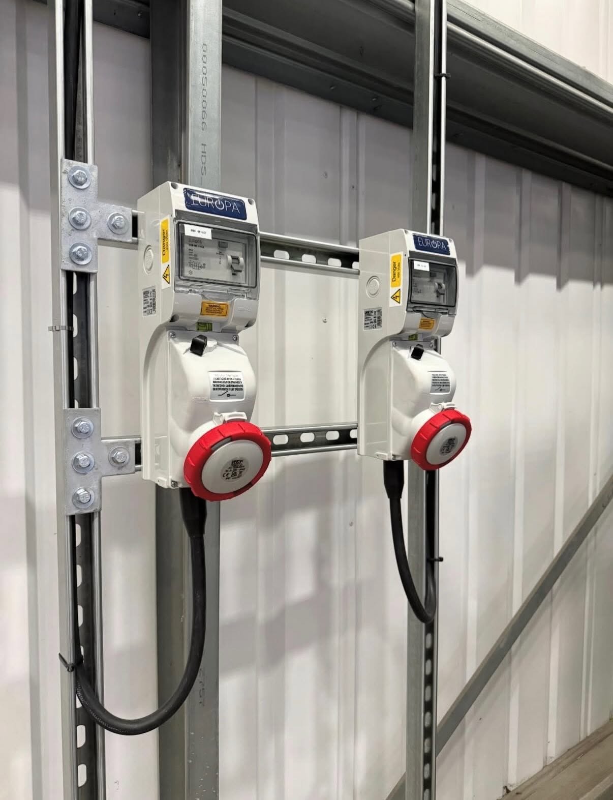 Two three phase hook-up units mounted on unistrut against profiled cladding on a commercial site