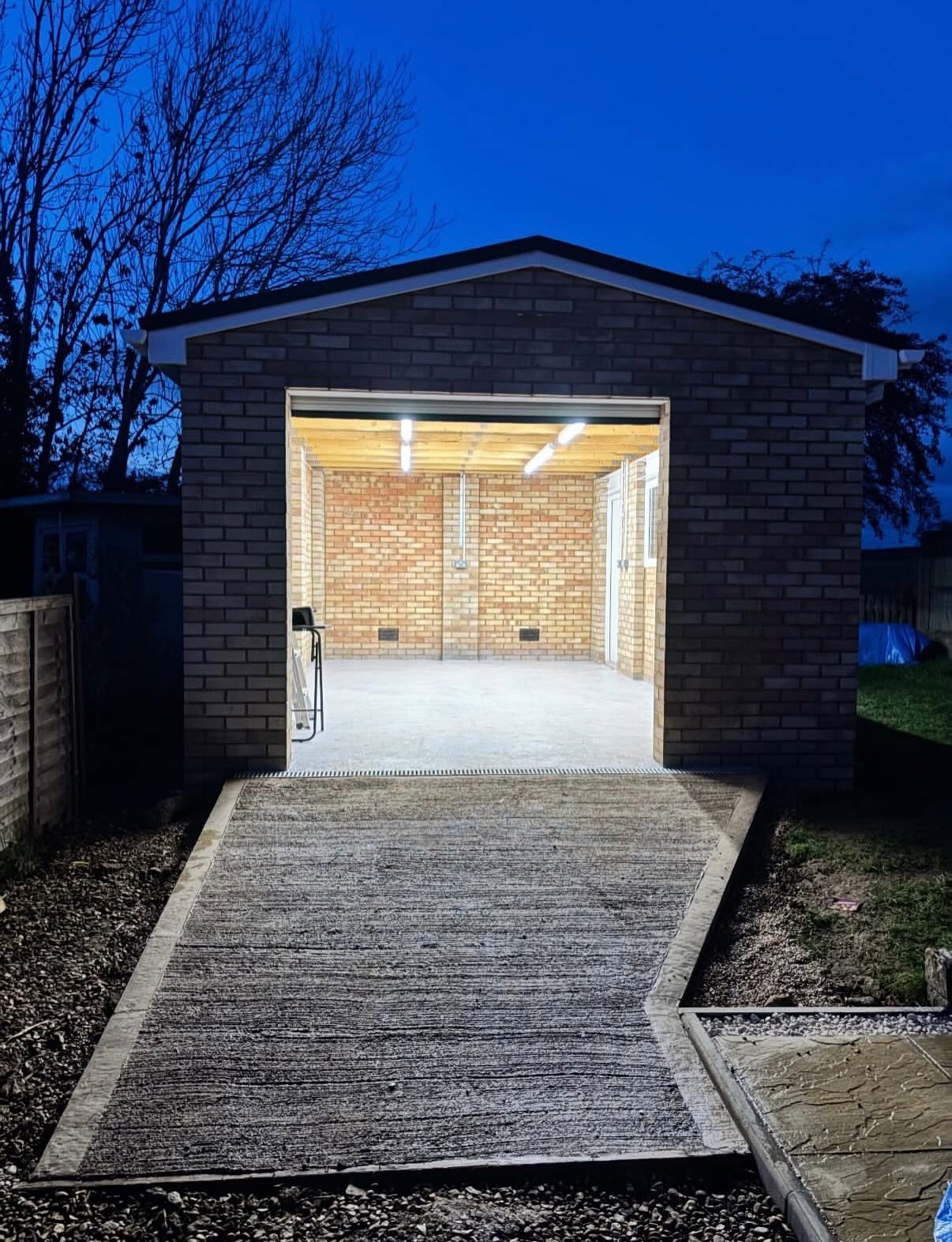 Garage conversion lit from inside at dusk after the electrical installation was completed
