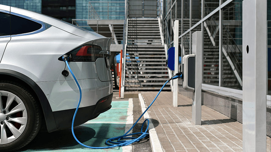 Electric car charging at workplace charging points outside a commercial building