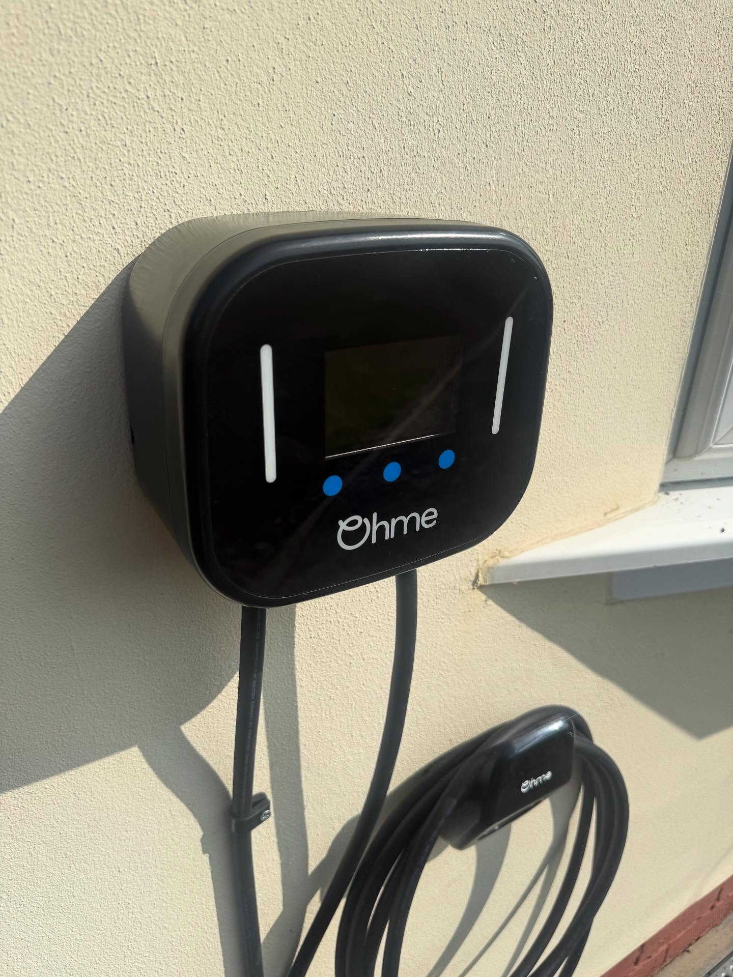 Ohme electric vehicle charger installed on a rendered house wall