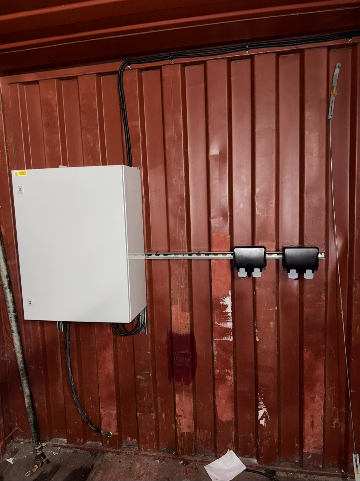 Distribution enclosure and twin sockets mounted on unistrut against a container wall