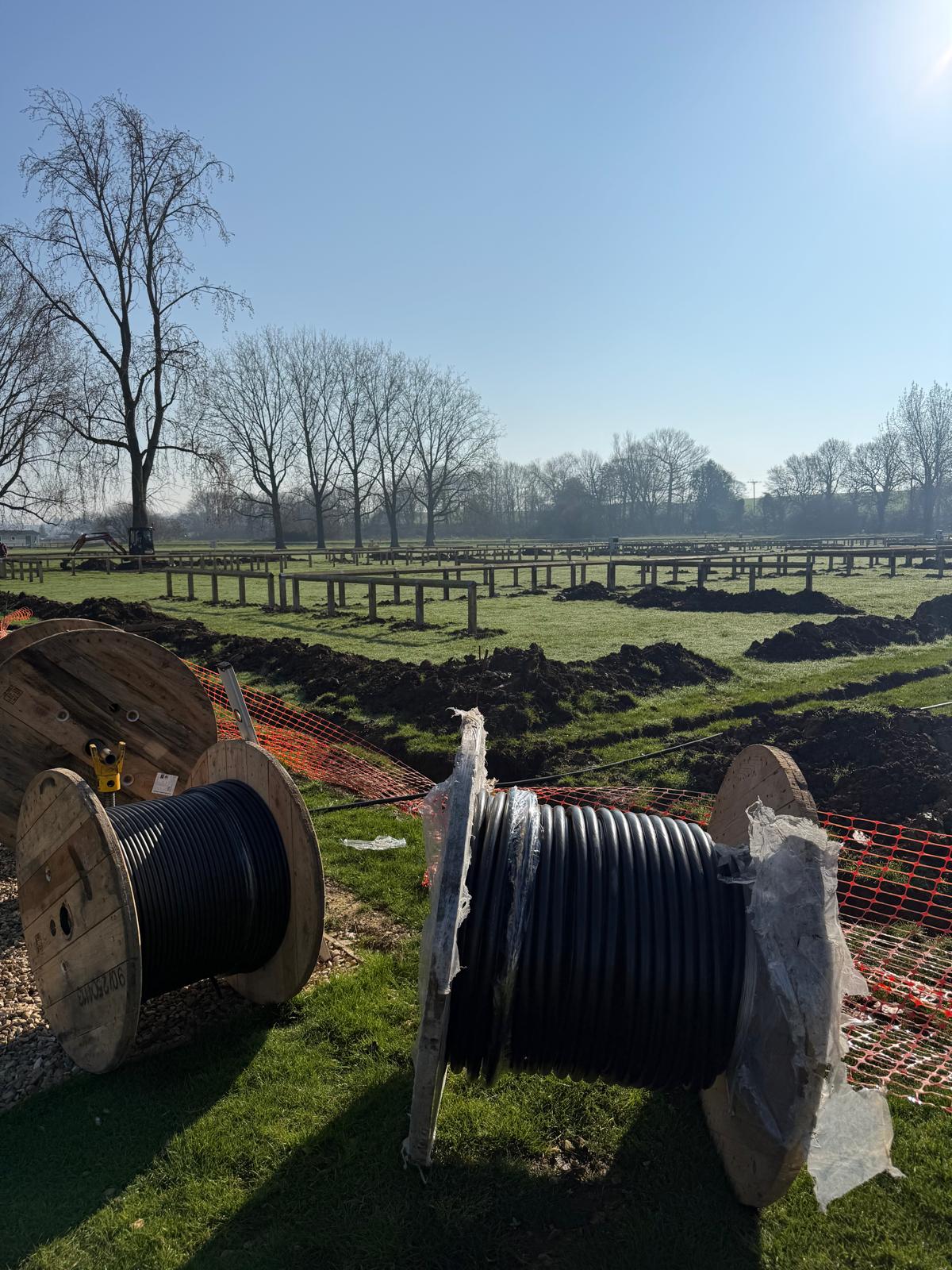 Cable drums and trenching across a field during the electrical installation for 60 new camping pitches