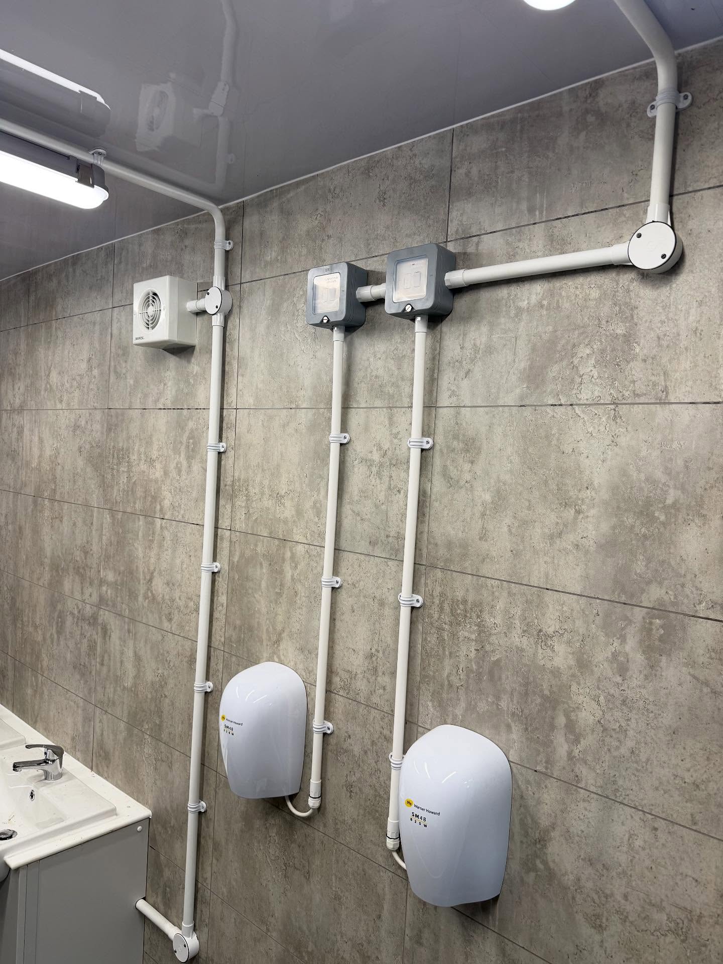 Surface conduit, hand dryers and extract fan wired in a commercial washroom